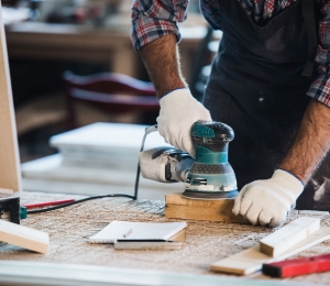 Worker grinds the wood of angular grinding machine